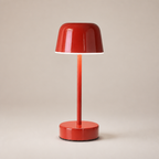 Glossy red cordless table lamp with dome shade and round base on a warm neutral backdrop.