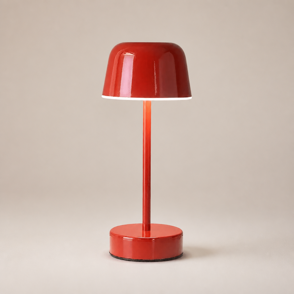 Glossy red cordless table lamp with dome shade and round base on a warm neutral backdrop.