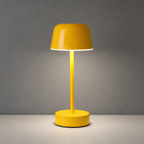 Glossy yellow cordless table lamp with a dome shade on a light tabletop.