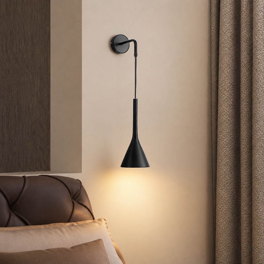 Black cone wall sconce glowing warmly beside a tufted leather headboard.