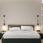 Gray pendant lamps flank a white bed with pillows and a low dark green platform.