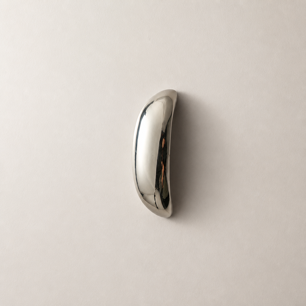 Polished chrome curved handle on a plain light surface.