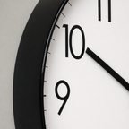 Close-up of a black-framed analog wall clock with a white face and bold black numerals.