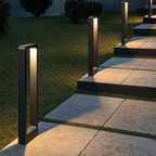 Black rectangular pathway bollard lights illuminate stone steps in a grassy garden.