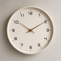 Beige wall clock with black numerals and slim wooden hands on a light wall.