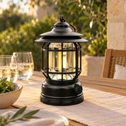 Black lantern on a verandah dining table on a summer evening.