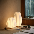 Two warm glowing ribbed paper floor lamps with wooden bases on a tatami mat floor.