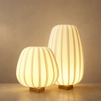 Two glowing ribbed fabric table lamps with warm wooden bases.