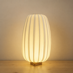 Glowing ribbed cream table lamp with a small wooden base on a neutral tabletop.