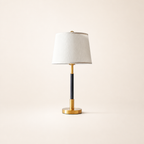 White shade table lamp with a black stem and polished gold base.