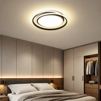 Round black ceiling light glows warmly above a modern bedroom with wardrobes.