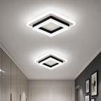 Two glowing square ceiling lights with white frames and black trim in a modern hallway.