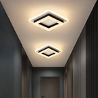 Two square black-and-white LED ceiling lights glowing warmly in a modern hallway.