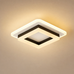 Square warm ceiling light with layered white frame and black inner trim glowing on a beige background.