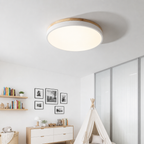 Round flush mount ceiling light with wood trim glowing in a bright children's room.