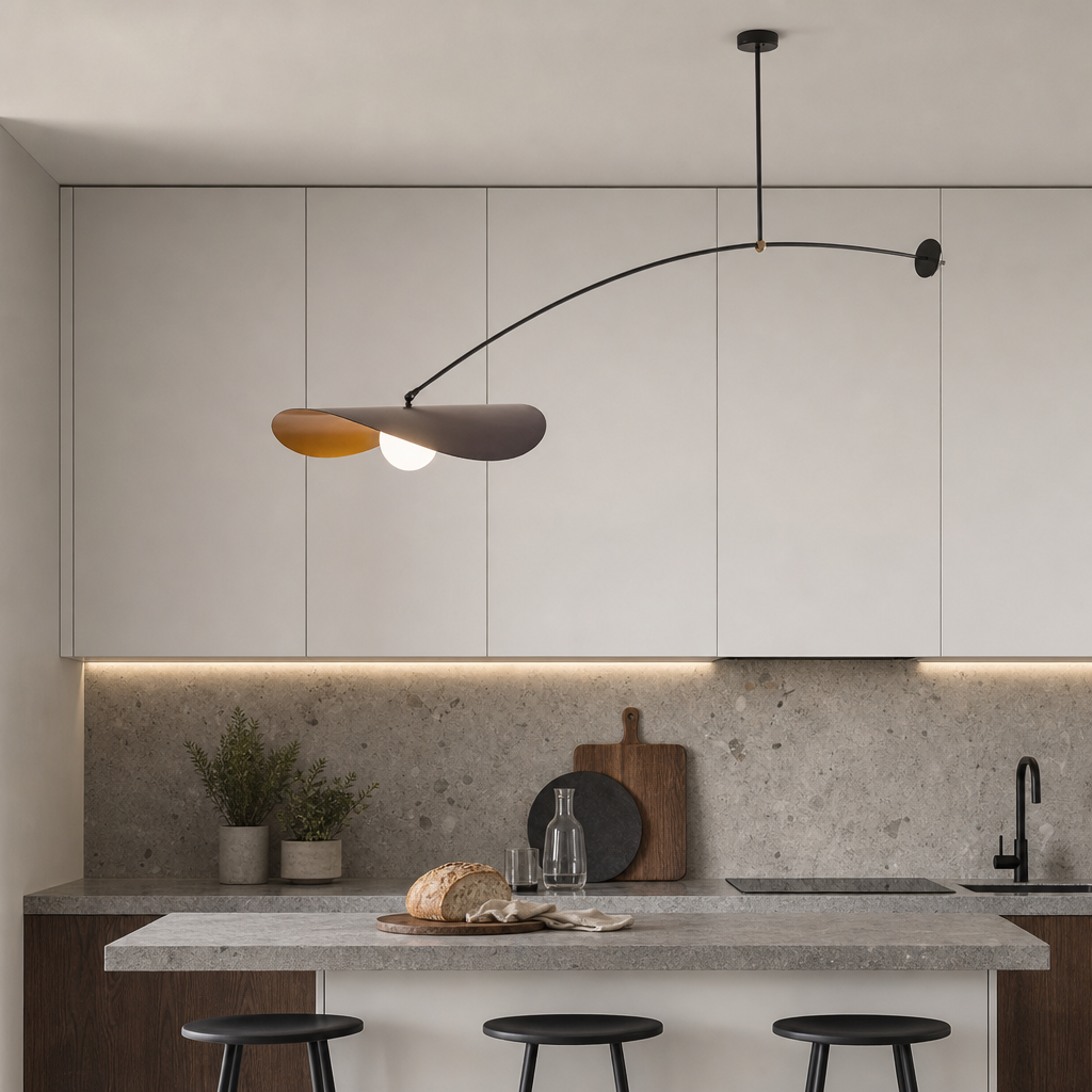 Curved pendant lamp over a modern kitchen with white cabinets, stone backsplash, and island stools.