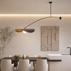 Modern arched pendant light with petal shades glowing above a minimalist dining table.