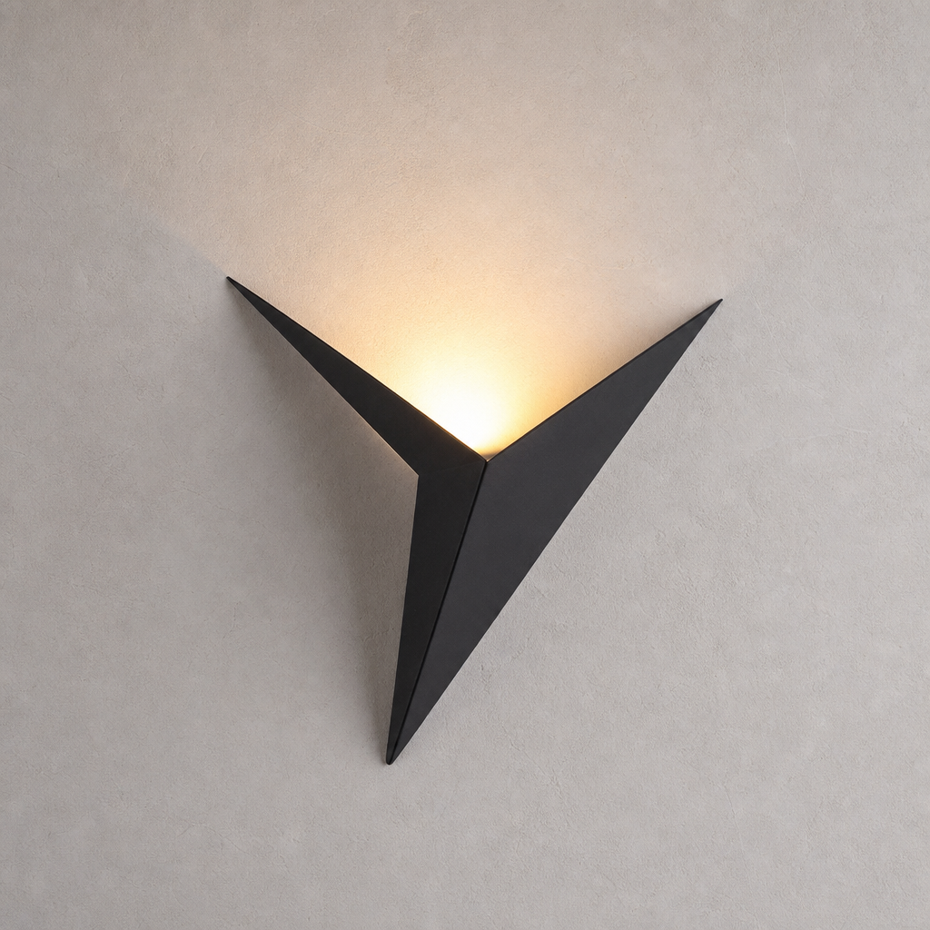 Black triangular wall sconce casting a warm upward glow on a pale textured wall.