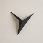 Black angular three-point wall decor mounted on a pale neutral wall.