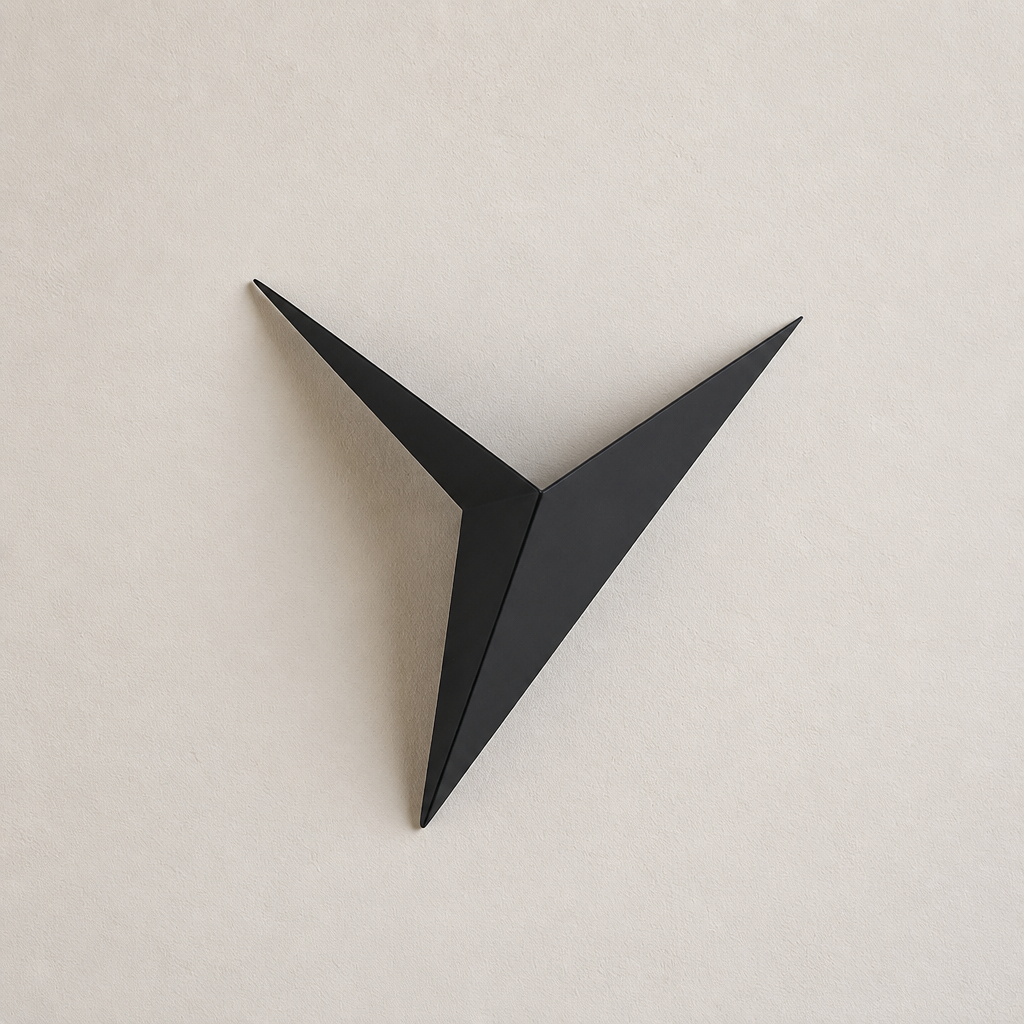 Black angular three-point wall decor mounted on a pale neutral wall.