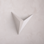 A minimalist, white, v-shaped Starry Night wall sconce against a textured, light-colored wall.