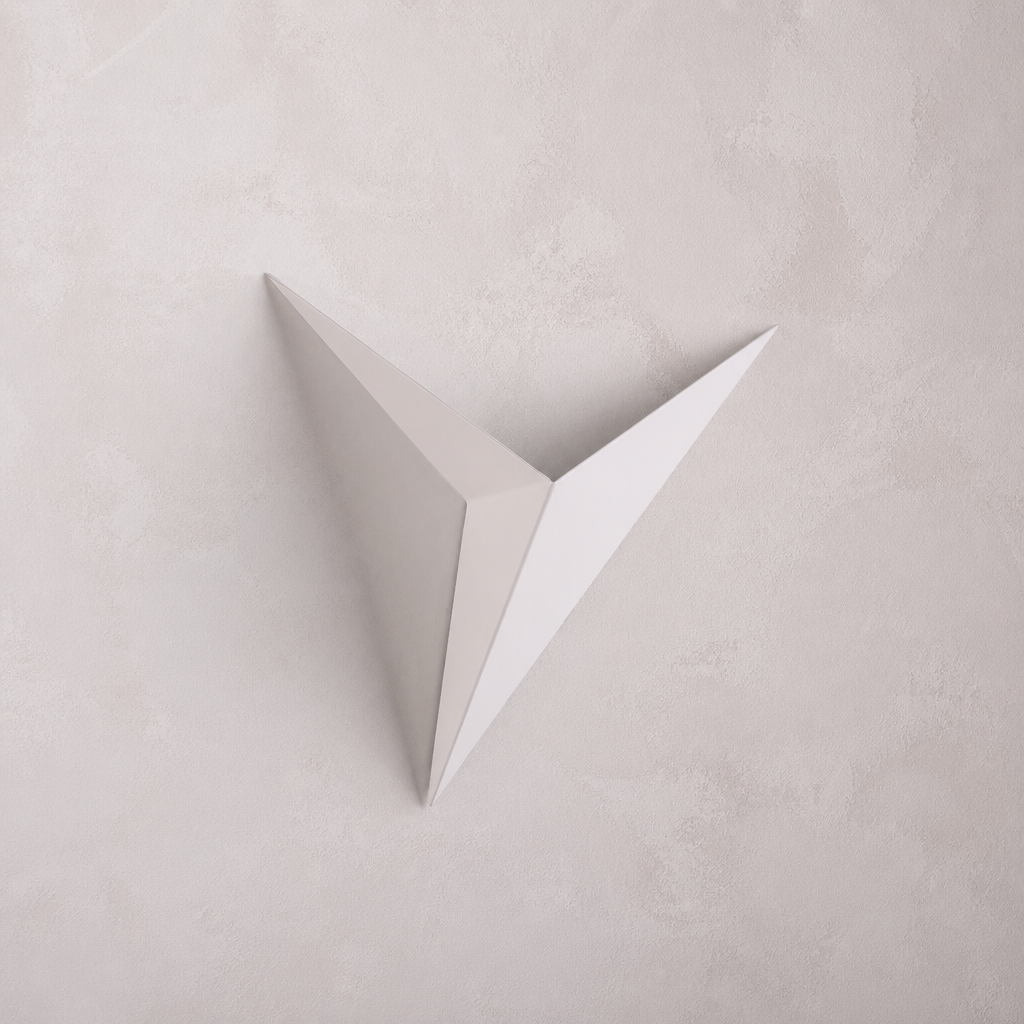 A minimalist, white, v-shaped Starry Night wall sconce against a textured, light-colored wall.