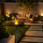 Black solar torch garden lights with warm flame LEDs lining a modern patio path.