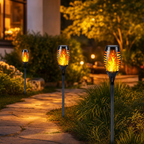 Three flame-style solar garden torches line a softly lit outdoor walkway.