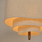 Layered beige fabric ceiling lamp with warm glow and a small wooden finial.