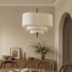 Tiered cream fabric pendant light hanging above a warm neutral dining room.