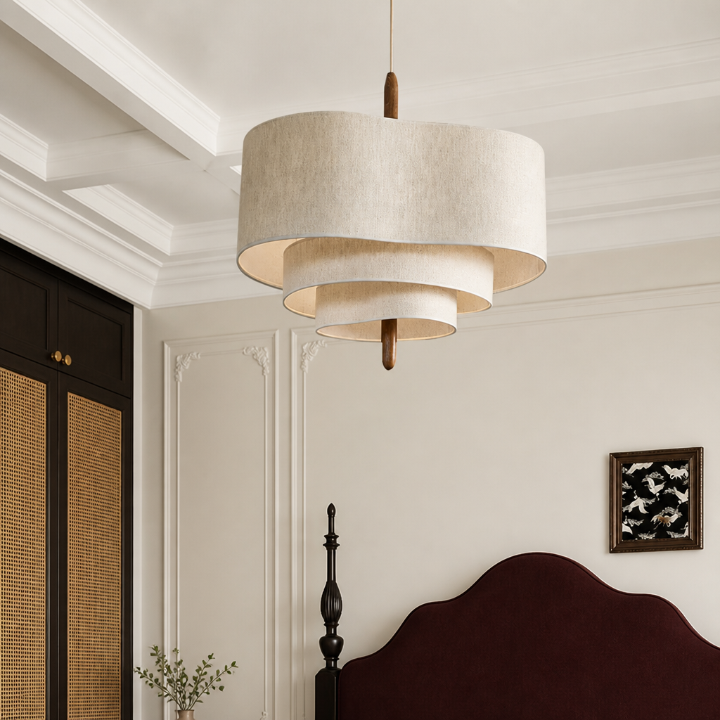 Tiered cream fabric pendant light hanging above an elegant bedroom with a red headboard.