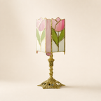 Pink tulip stained glass table lamp with ornate gold base on a pale neutral background.