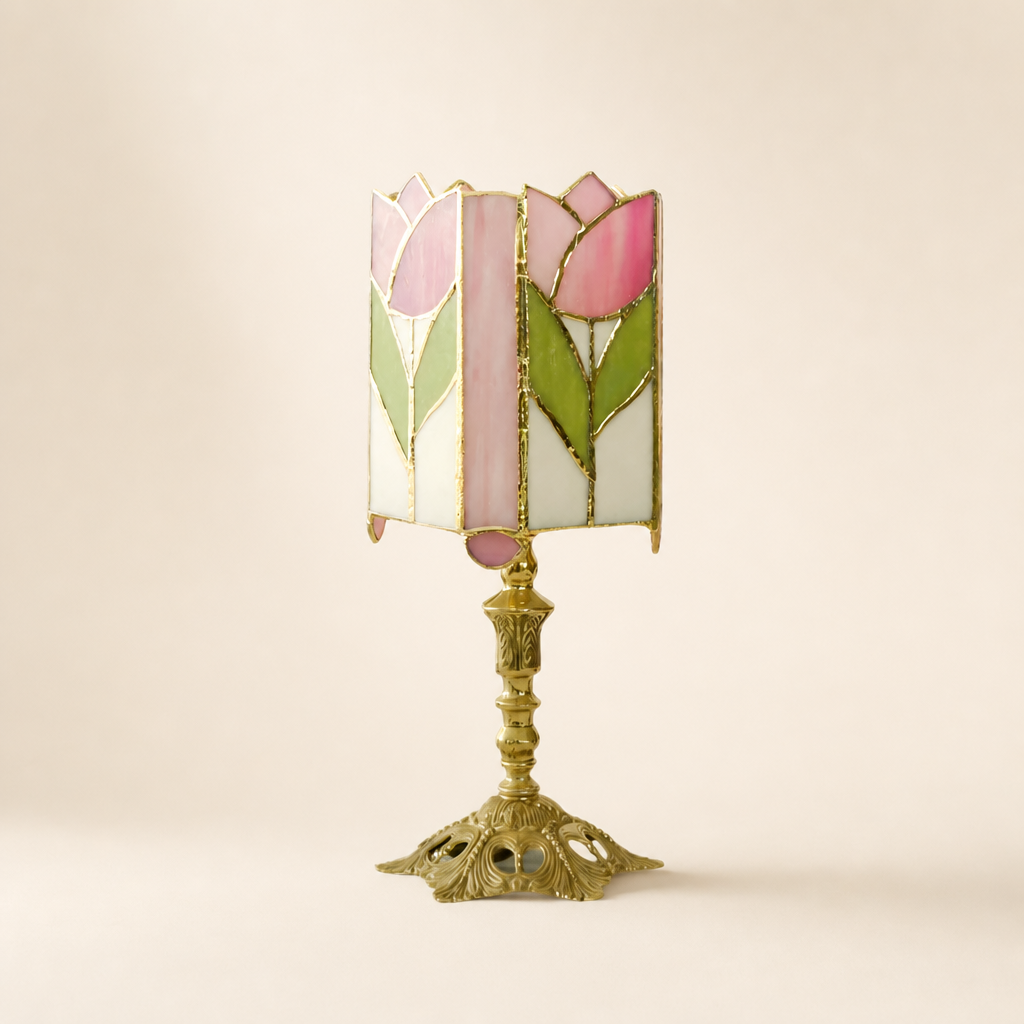 Pink tulip stained glass table lamp with ornate gold base on a pale neutral background.
