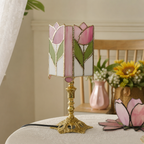 Pink tulip stained glass table lamp with an ornate gold base on a table.