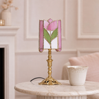 Pink floral stained-glass table lamp with ornate gold base on a marble side table.