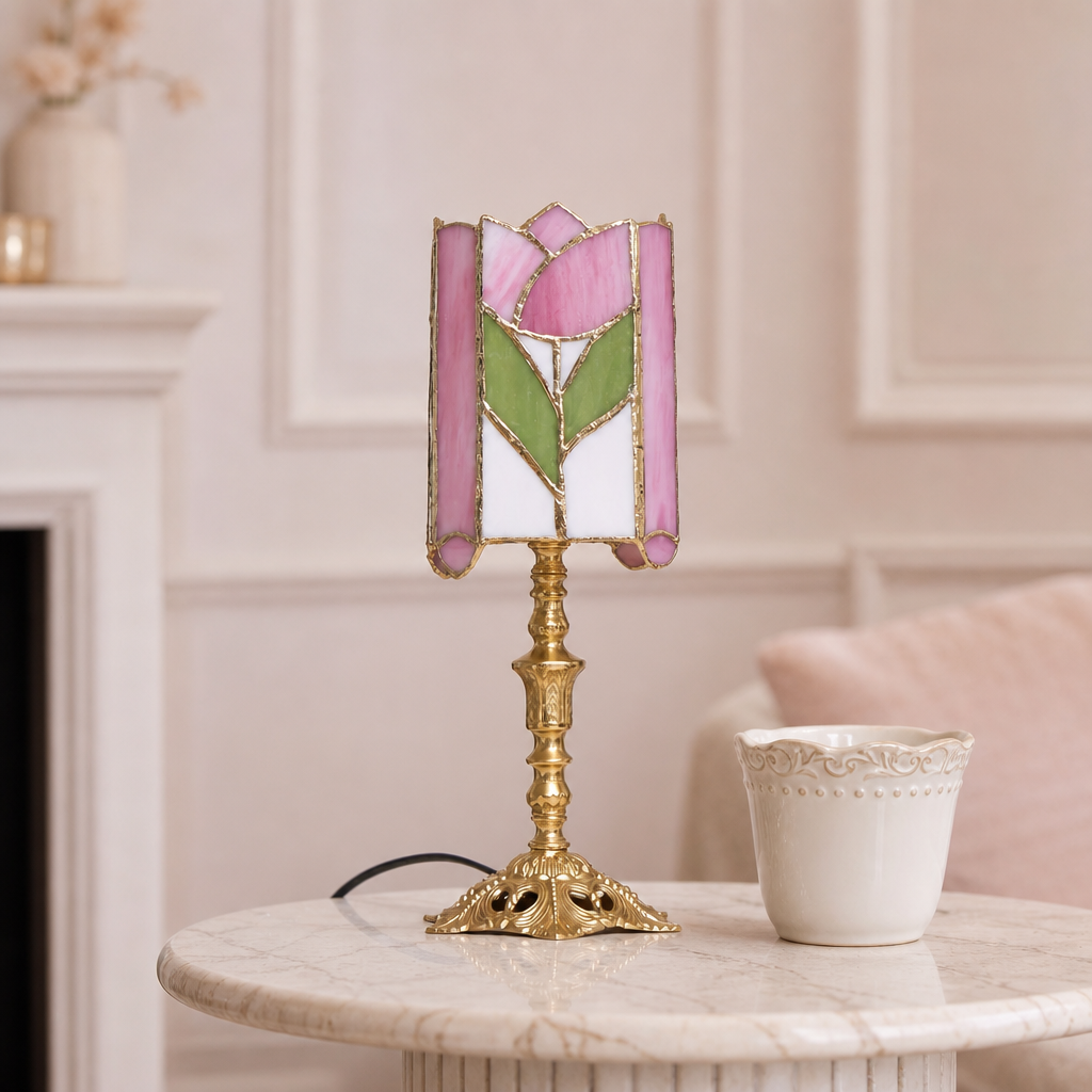 Pink floral stained-glass table lamp with ornate gold base on a marble side table.