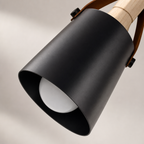 Black cylindrical pendant lamp shade with wood detail and visible white bulb.
