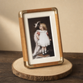 Wood and brass photo frame with a girl and dog portrait leaning on a wooden slice.
