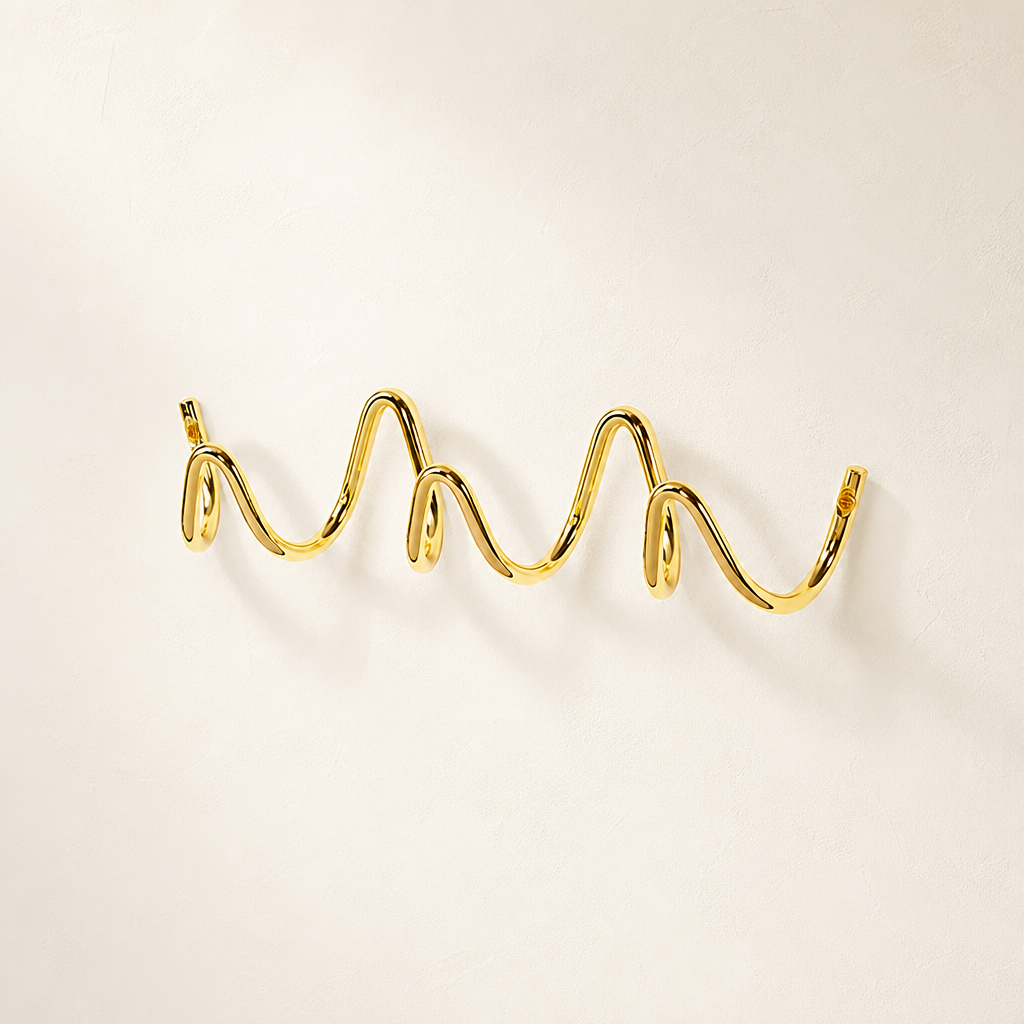 Polished gold wavy wall hook rack on a clean light background.