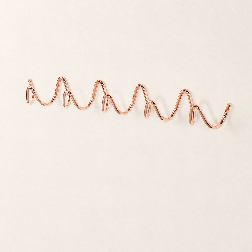 Rose gold wavy wall rack with multiple rounded hooks on a clean white surface.