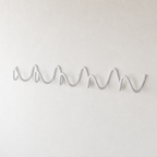 White wave-shaped wall hook rack mounted on a plain white textured wall.