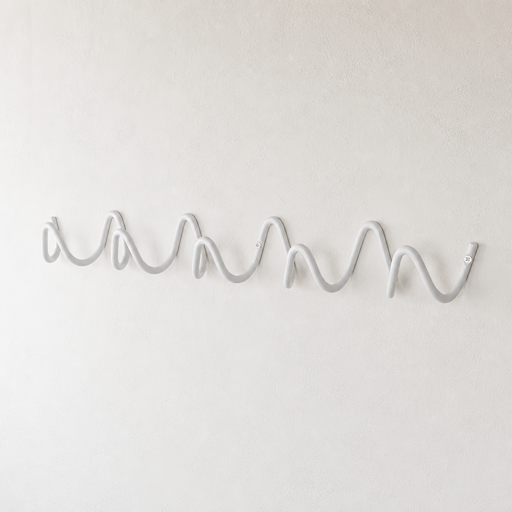 White wave-shaped wall hook rack mounted on a plain white textured wall.