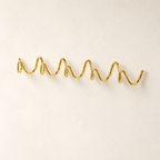 Gold wavy wall-mounted hook rack on a clean white background.