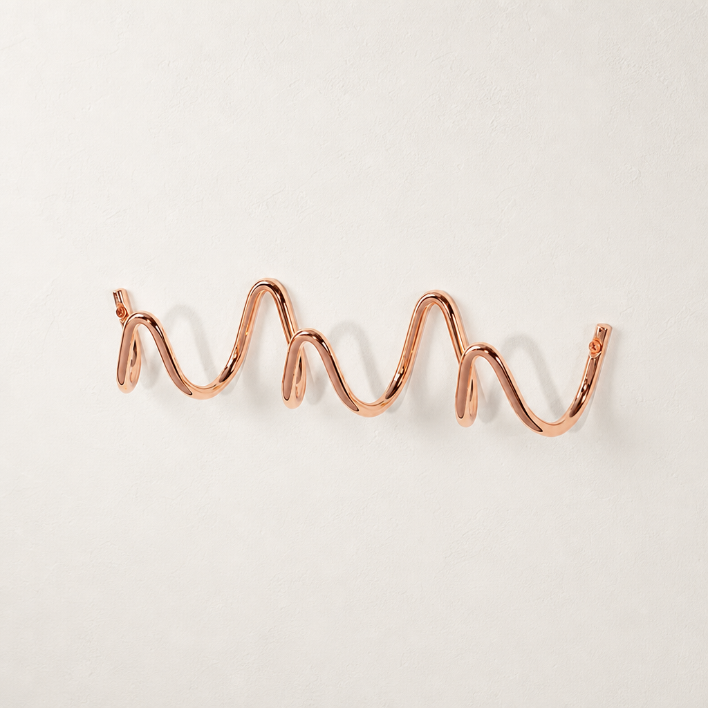 Rose gold wavy wall-mounted hook rail on a clean white surface.