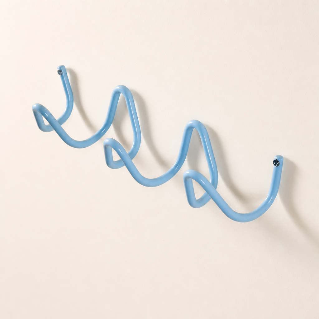 Light blue wavy wall-mounted hook rack with screw caps on a plain wall.