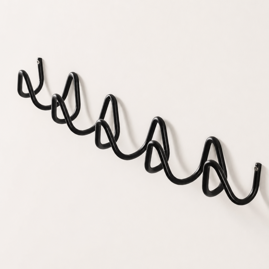 Black wavy metal wall rack with multiple curved hooks on a plain light wall.