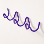 Purple wavy wall-mounted metal rack with visible end screws on a plain light wall.
