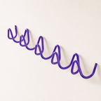 Purple wavy wall-mounted rack with repeating loop hooks on a clean white background.