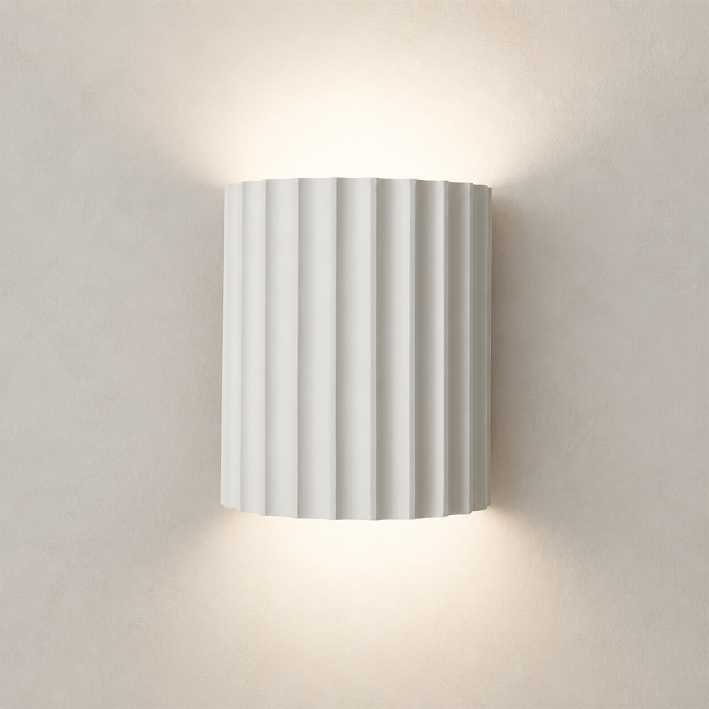White ribbed cylindrical wall sconce glowing warmly on a plain wall