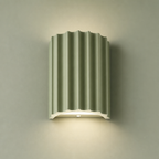 Sage green fluted wall lamp with a white base casting a soft downward glow.